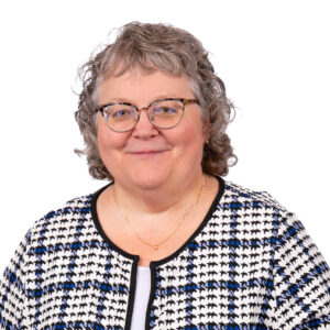 A photo of Judi Leibbrand, deputy executive director. She has short hair and glasses and is wearing a checkered shirt.